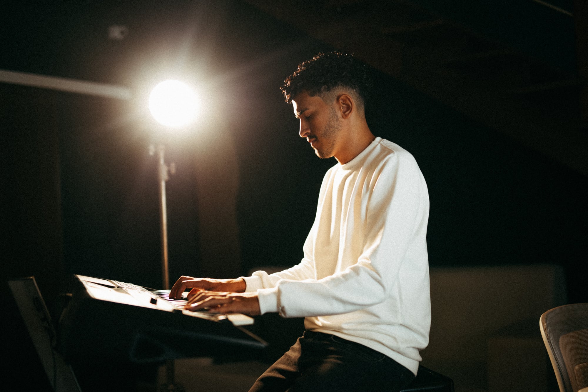 Maurynho Ramos tocando teclado arranjador Yamaha num palco escuro
